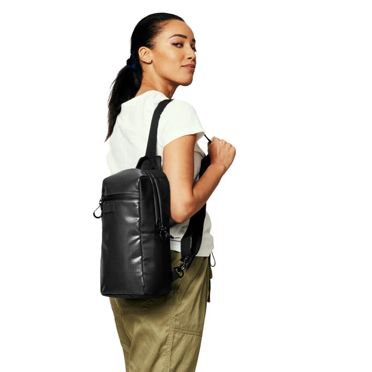 Modelo com a bolsa Nixon Syndicate Sling Bag Asphalt junto à anca, mostrando a alça sobre o ombro e a fixação lateral.