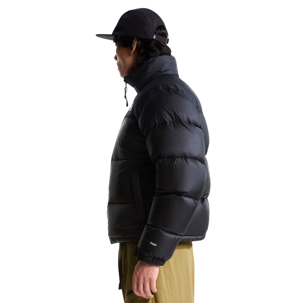 Casaco The North Face 1996 Retro Nuptse preto em modelo de perfil, com gola alta, manga volumosa e bordado 700 junto ao punho.