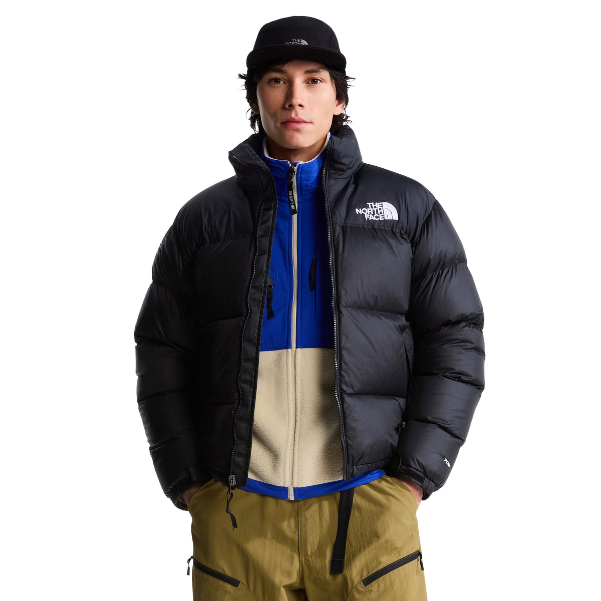 Casaco The North Face 1996 Retro Nuptse preto aberto em modelo de frente, sobre uma peça azul e bege, com logótipo branco no peito.