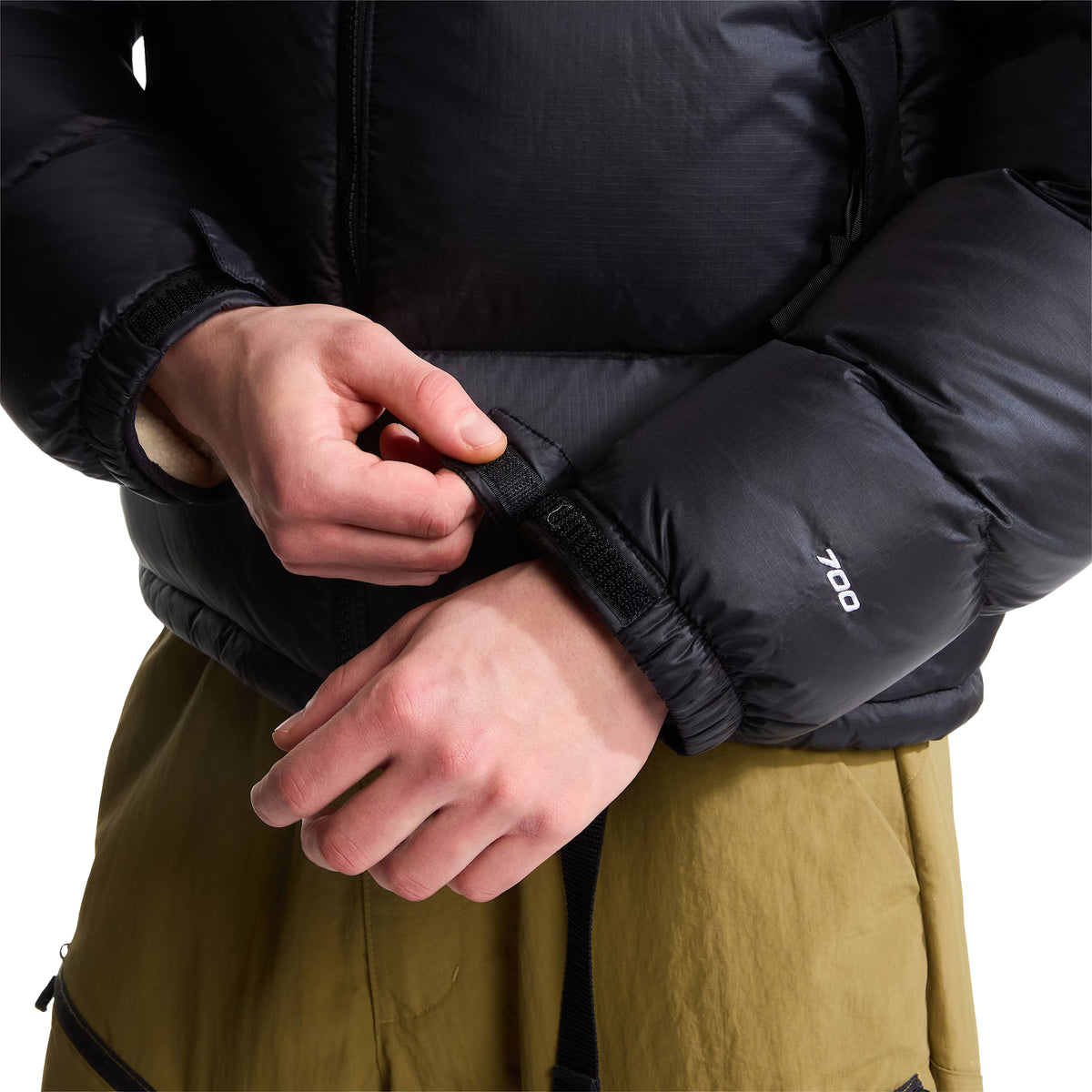Pormenor do punho do casaco The North Face 1996 Retro Nuptse preto, com aba de velcro em ajuste e bordado branco 700 na manga.
