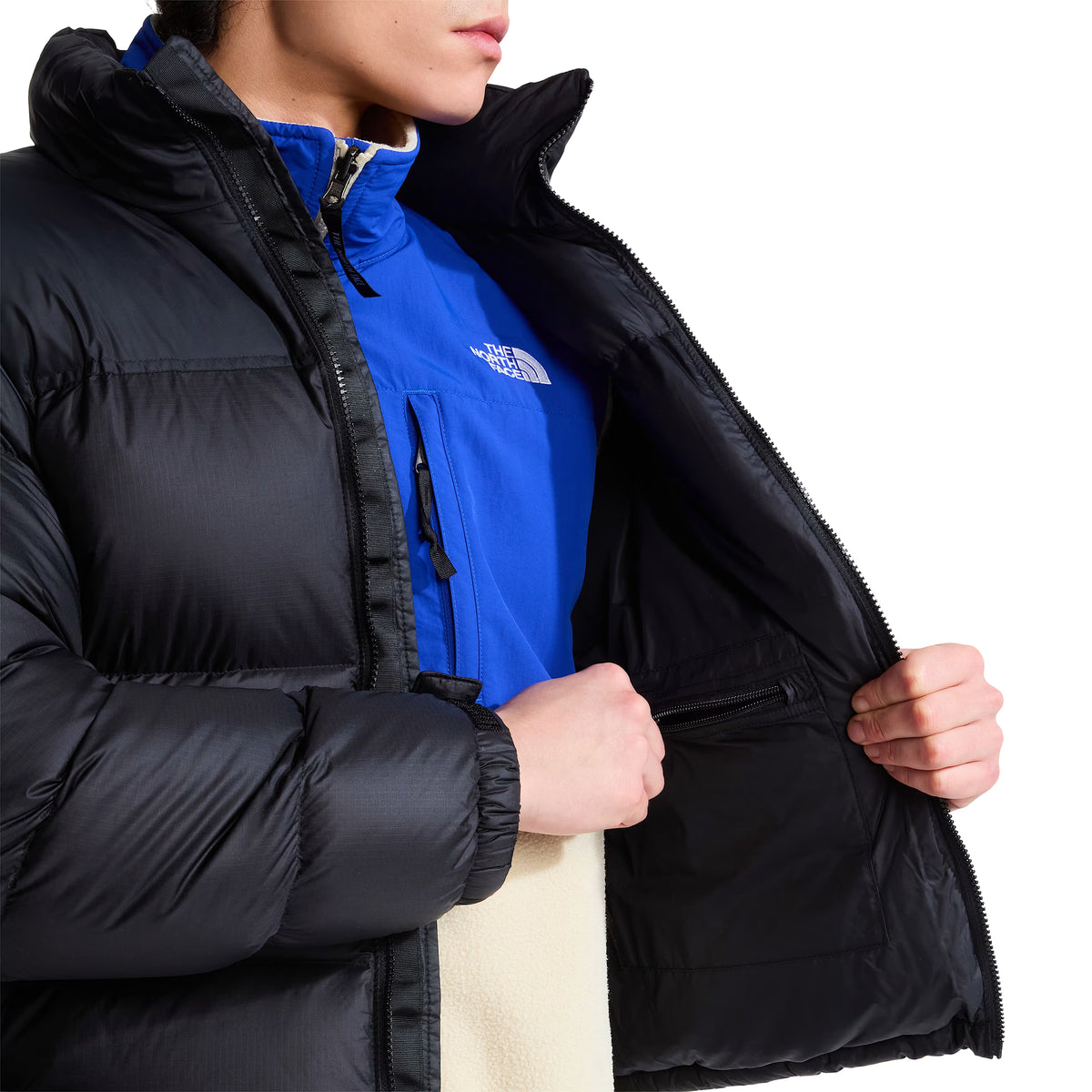 Interior do casaco The North Face 1996 Retro Nuptse preto, aberto pelo modelo para mostrar o forro e o bolso interior com fecho de correr.
