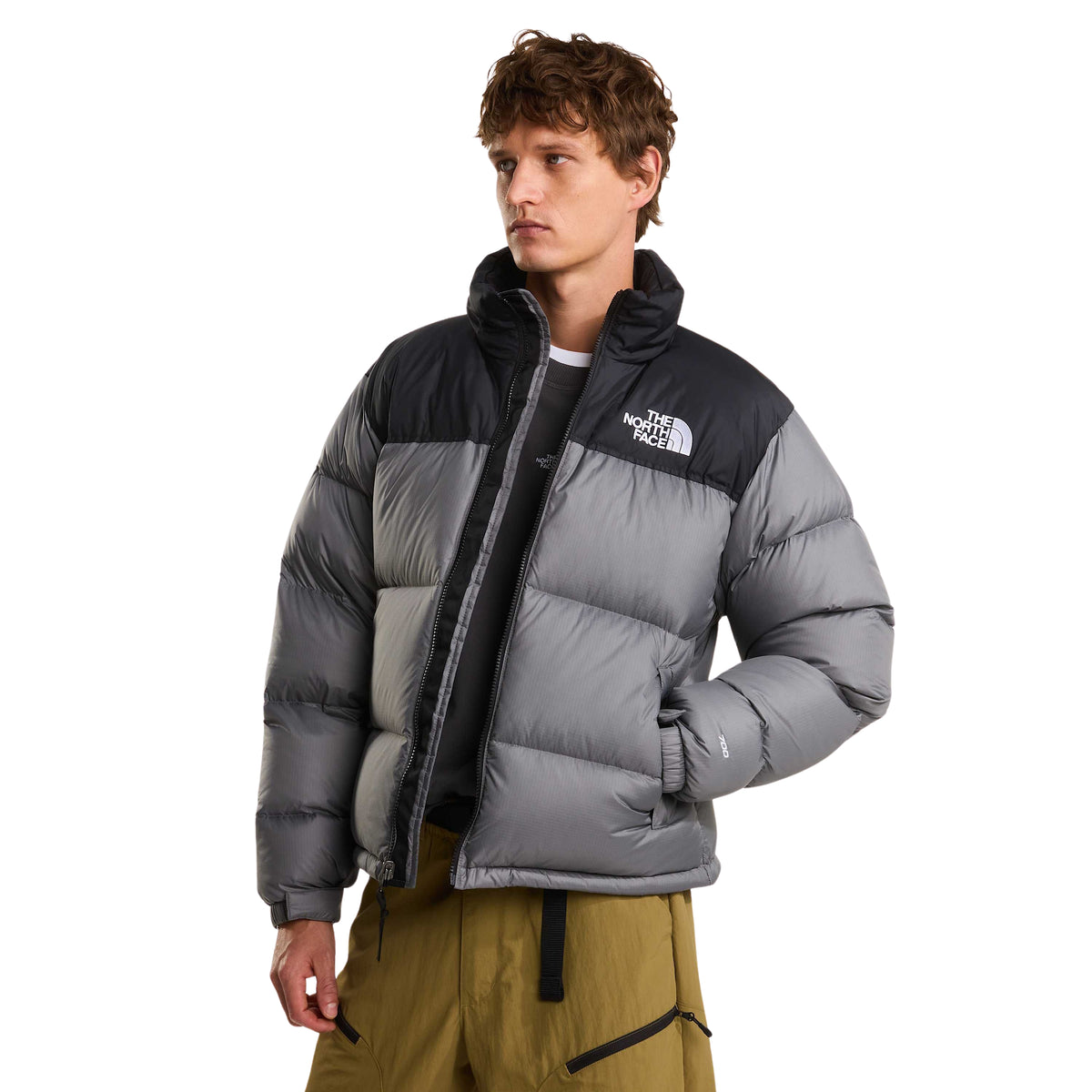 Casaco The North Face 1996 Retro Nuptse cinzento e preto vestido de frente, aberto e com uma mão no bolso.