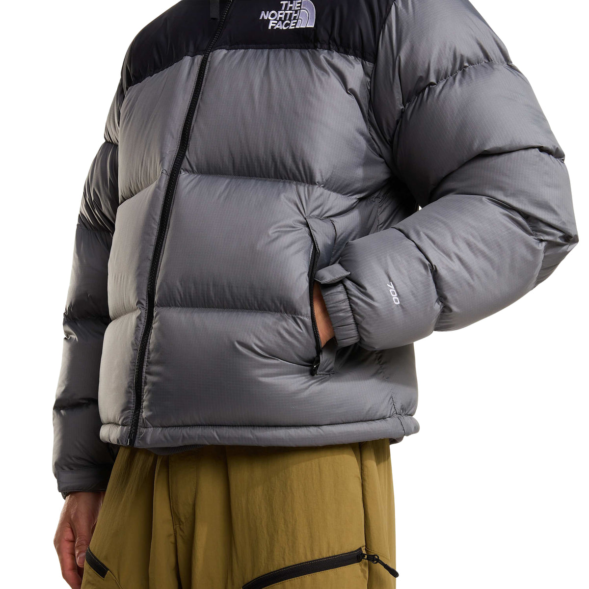 Pormenor do bolso lateral com fecho, dos painéis acolchoados e do bordado 700 na manga do casaco The North Face Nuptse.