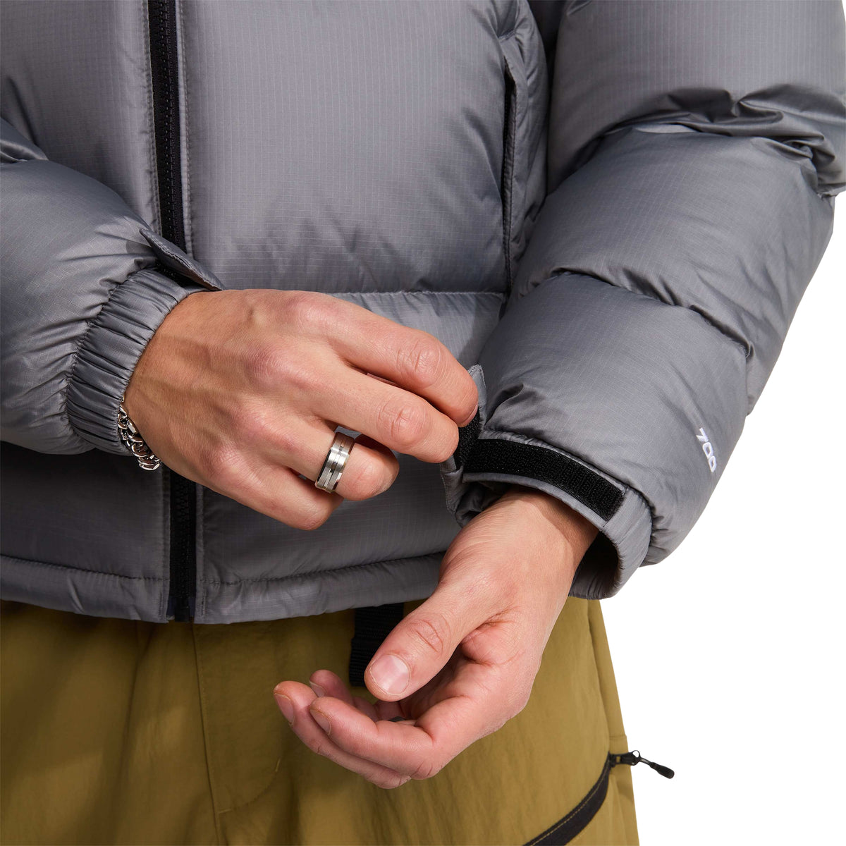 Pormenor do ajuste em velcro no punho e do bordado 700 na manga cinzenta do casaco The North Face 1996 Retro Nuptse.