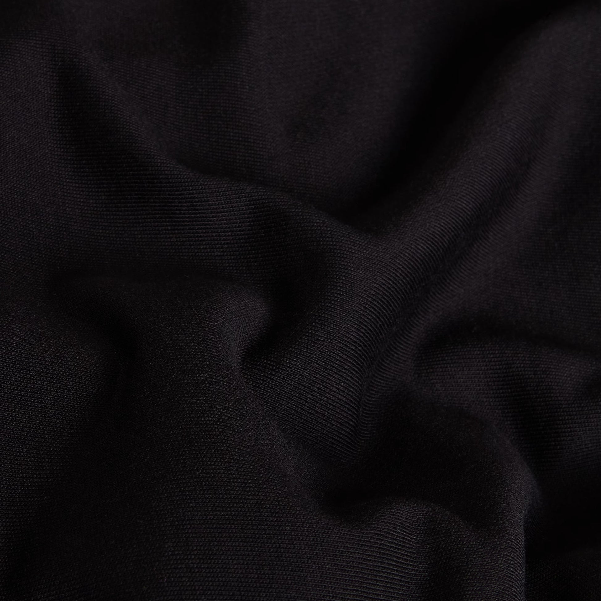 Hoodie The North Face Apex '75 Collage Relaxed em TNF Black — detalhe do tecido cardado em TNF Black, textura de malha 360 g/m² com dobras suaves visíveis em close-up, fundo preto.