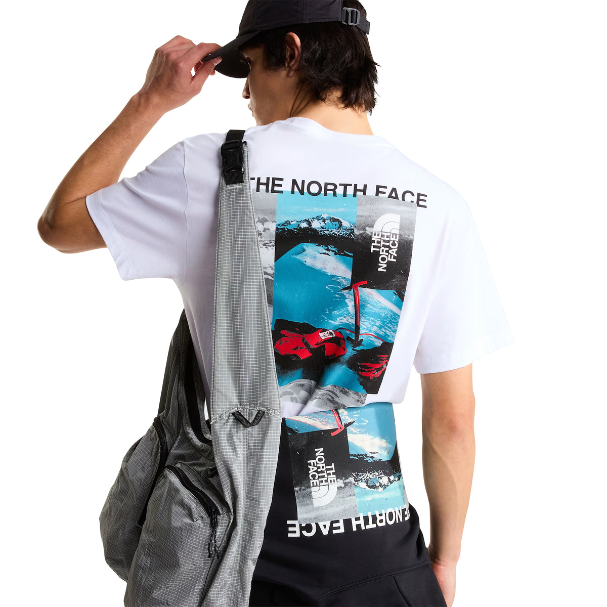 T-shirt de manga curta The North Face Apex '75 Collage em branco — modelo masculino de costas, pormenor do gráfico collage: "THE NORTH FACE" em preto, collage com montanha nevada em azul/cinzento, luvas de ski vermelhas TNF e logótipo TNF vertical, corte relaxed, boné preto, fundo branco.