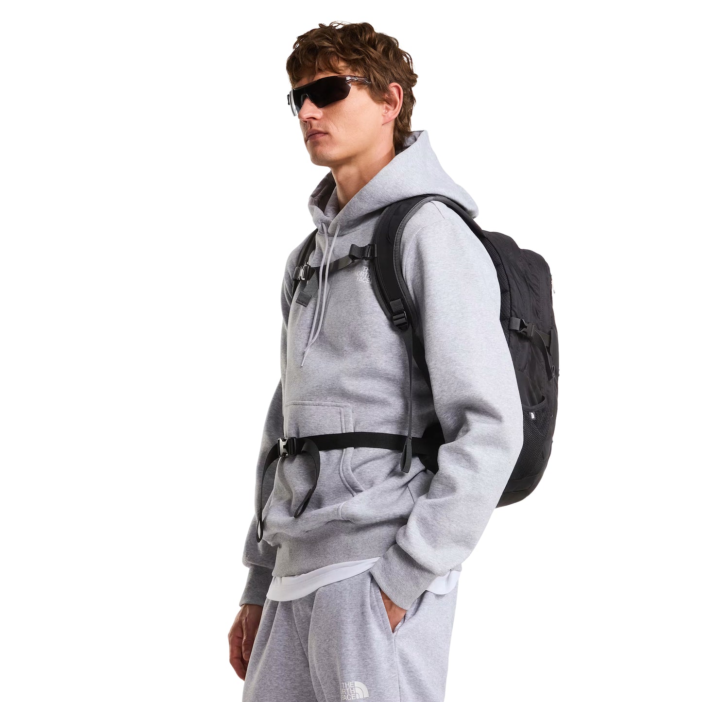Mochila The North Face Borealis Classic em TNF Black / Asphalt Grey — modelo de perfil a 3/4, meio corpo, hoodie TNF cinzento claro, mochila Borealis Classic TNF Black bem visível às costas com alças FlexVent, fivela de peito ajustada e painel traseiro ventilado.
