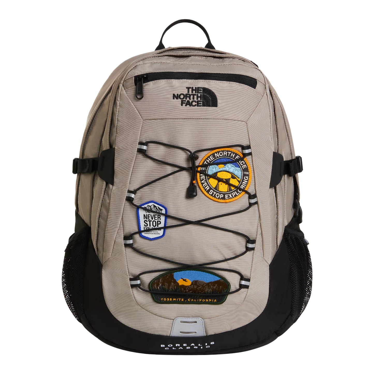 Mochila The North Face Borealis Classic Patch em Stone Slab / TNF Black — vista frontal, produto sem modelo, 3 patches bordados visíveis: circular amarelo/laranja "Never Stop Exploring", hexagonal azul com montanhas e oval Yosemite California, sistema de cordas elásticas, logo TNF bordado em preto e alças laterais pretas.