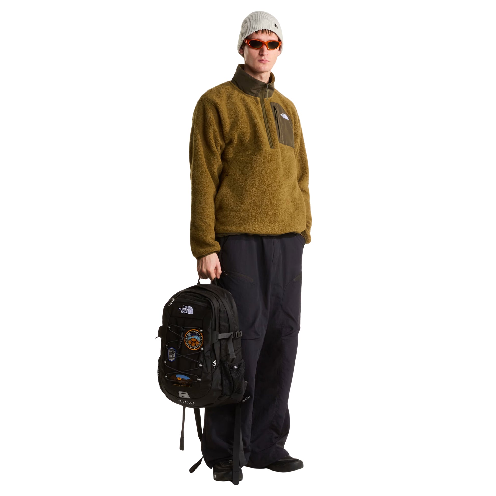 Mochila The North Face Borealis Classic Patch em TNF Black — detalhe dos 3 patches bordados: circular laranja/amarelo "Never Stop Exploring" 1966, hexagonal azul "Never Stop Exploring" com picos nevados e oval Yosemite California, sobre fundo TNF Black com cordas elásticas pretas