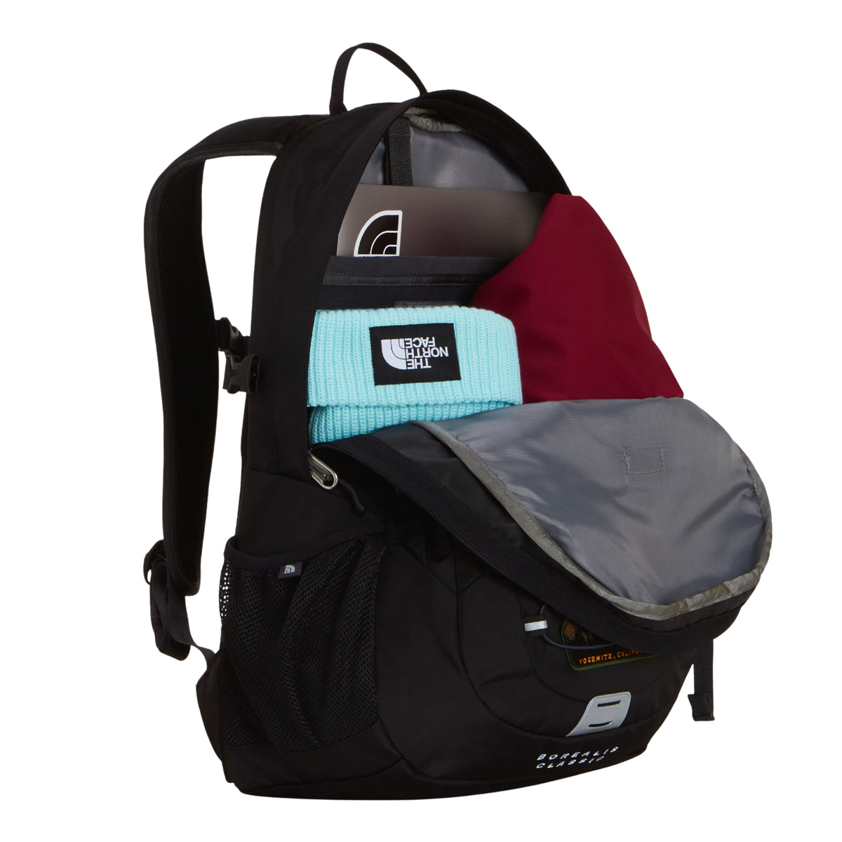 Mochila The North Face Borealis Classic Patch em TNF Black — interior aberto com compartimento principal, laptop TNF preto, sweat vermelha, gorro TNF azul claro e bolso organizador em Asphalt Grey visíveis.