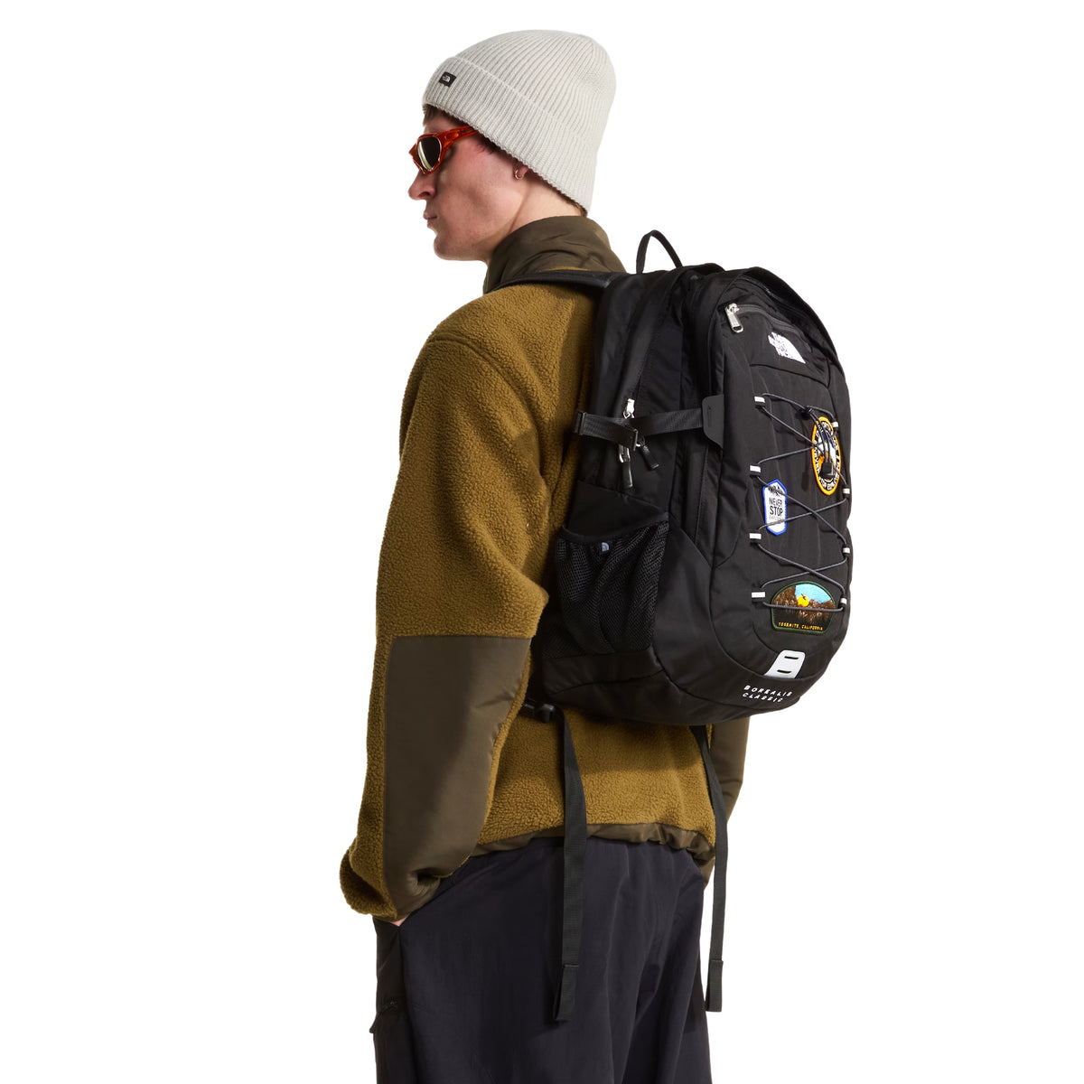 Mochila The North Face Borealis Classic Patch em TNF Black — vista frontal a 3/4 com modelo em ambiente urbano, patches bordados e sistema de cordas elásticas visíveis, alças ajustadas ao corpo