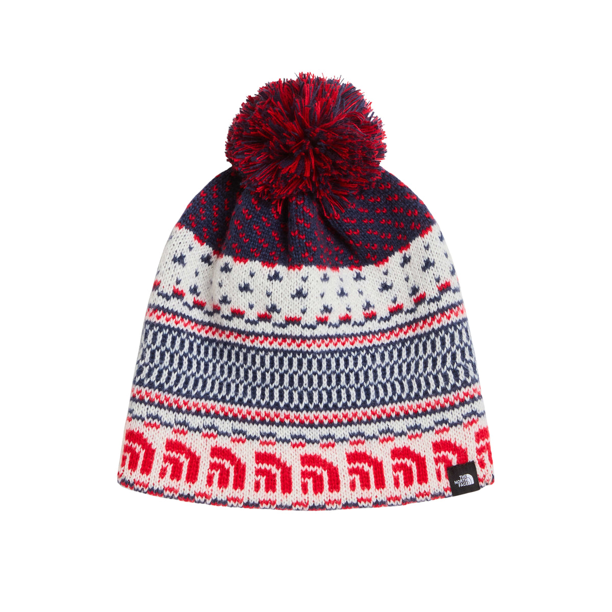 Gorro The North Face Cabin Ski Tuke White Dune Jacquard, com padrão em cru, azul-escuro e vermelho e pompom bicolor.