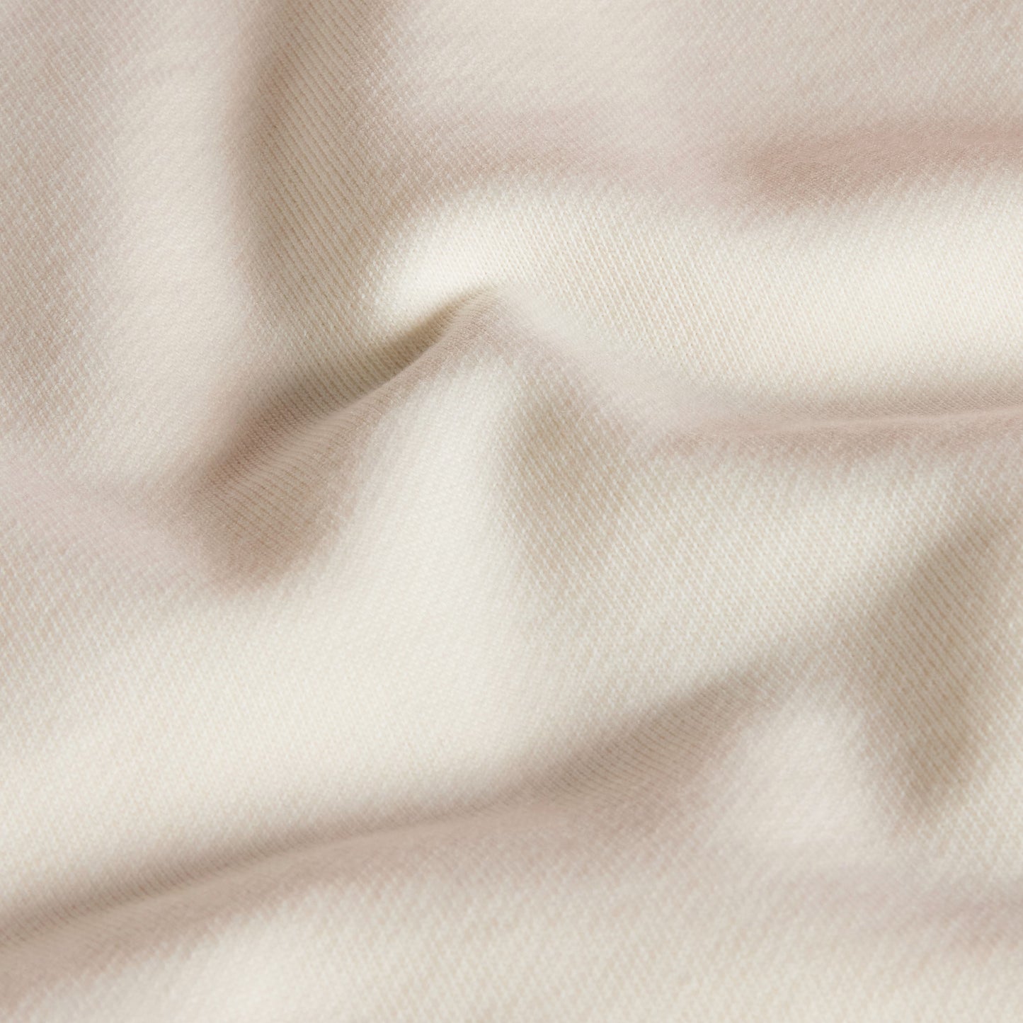 Hoodie unissexo The North Face Explorer Badges Relaxed em White Dune — detalhe da textura do French Terry, close-up do tecido 360 g/m² 60% algodão 40% poliéster em White Dune com dobras naturais, textura macia e estrutura do French Terry visíveis, fundo neutro.