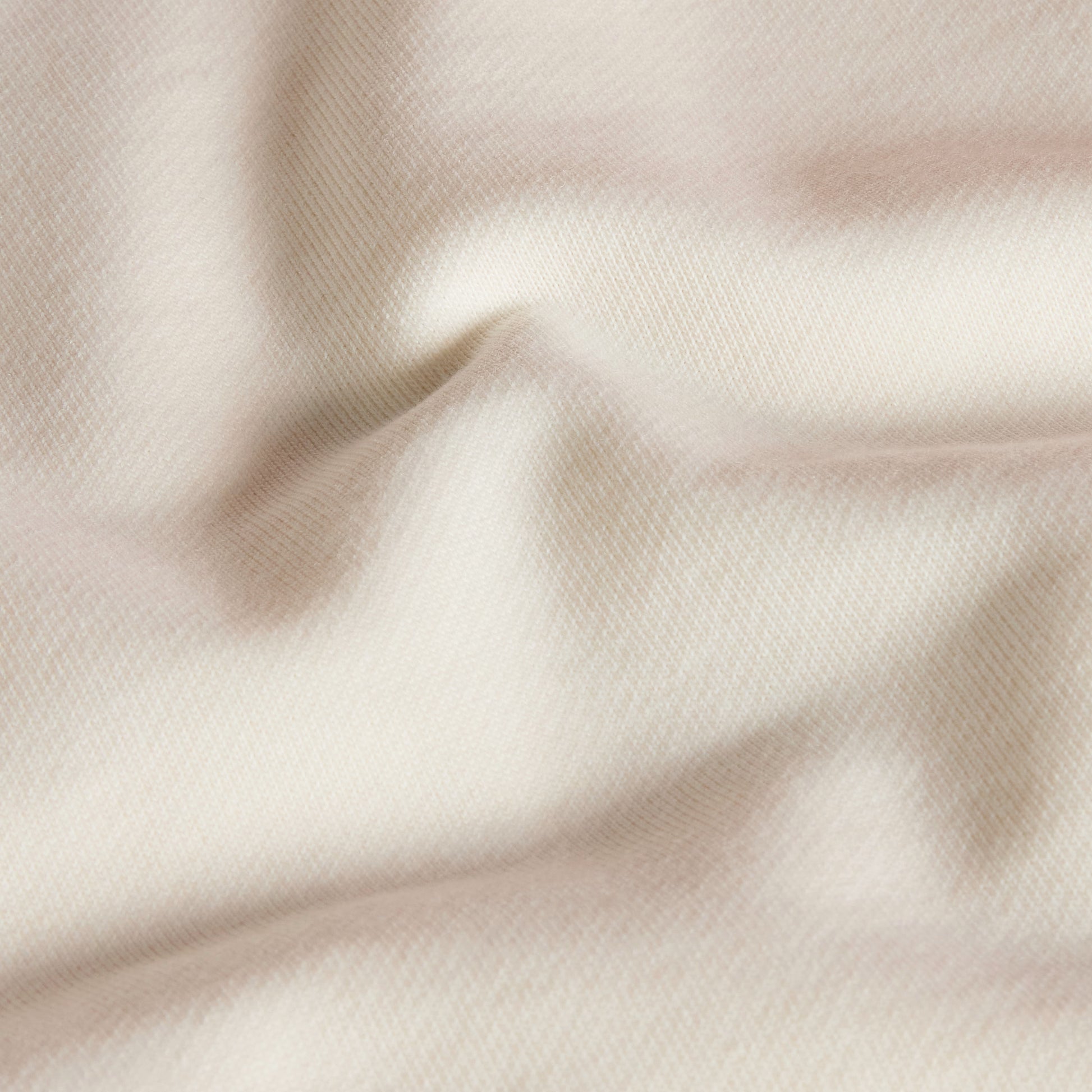Hoodie unissexo The North Face Explorer Badges Relaxed em White Dune — detalhe da textura do French Terry, close-up do tecido 360 g/m² 60% algodão 40% poliéster em White Dune com dobras naturais, textura macia e estrutura do French Terry visíveis, fundo neutro.