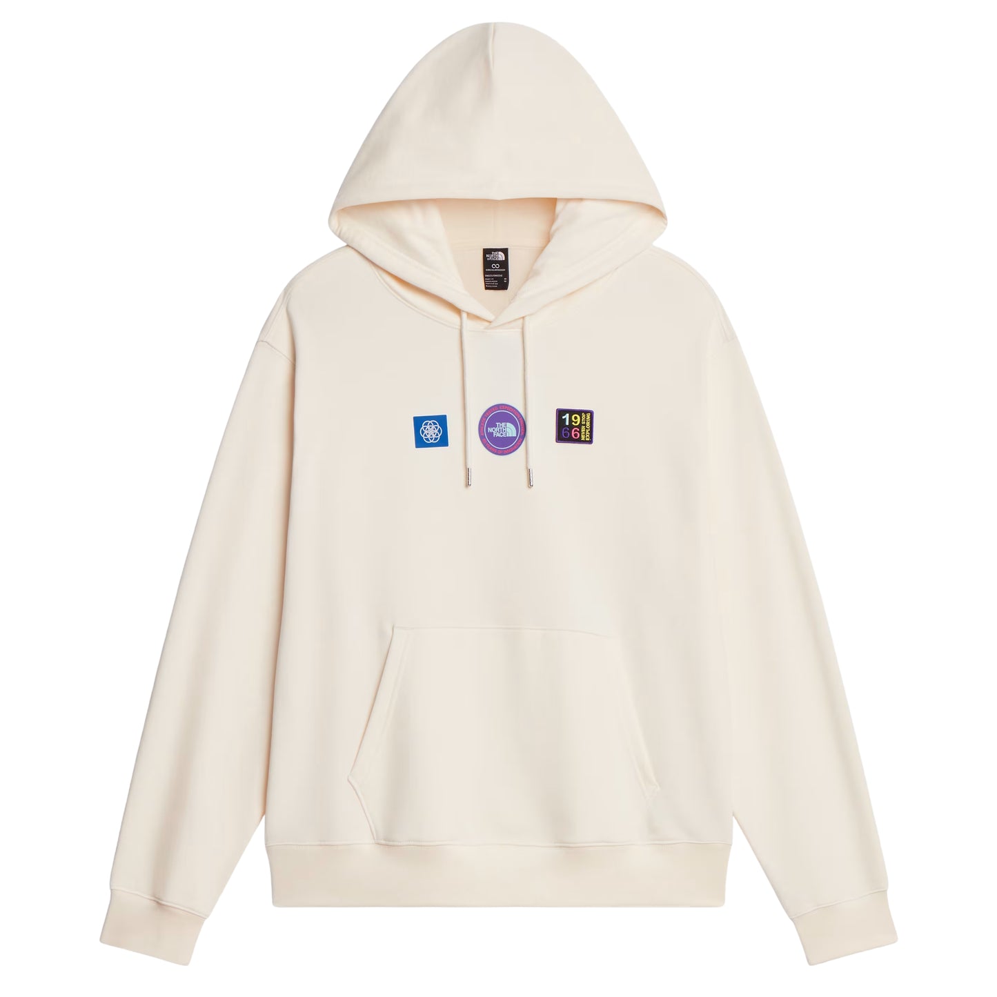 Hoodie unissexo The North Face Explorer Badges Relaxed em White Dune — vista frontal, produto sem modelo, etiqueta TNF na gola interior visível, três emblemas Explorer estampados em serigrafia à base de água no peito (azul quadrado com globo, circular roxo "The North Face", retangular escuro "1966 Never Stop Exploring" multicolor), capuz com cordão branco, bolso canguru e bainha canelada visíveis, French Terry White Dune 360 g/m², fundo branco.