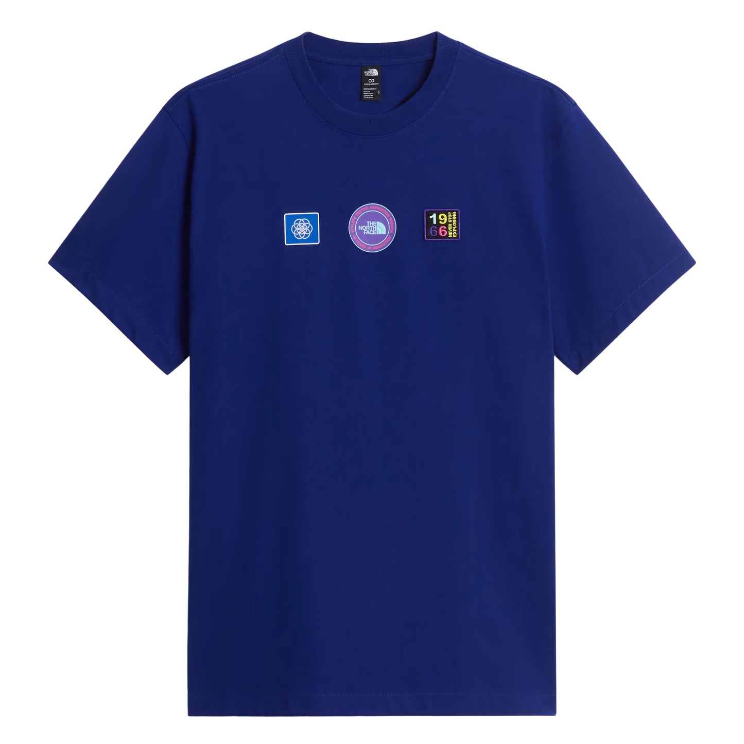 T-shirt unissexo The North Face Explorer Badges Relaxed em Bold Blue — vista frontal, produto sem modelo, três emblemas Explorer estampados em serigrafia à base de água no peito (azul quadrado com globo, circular roxo "The North Face", retangular escuro "1966 Never Stop Exploring" multicolor), etiqueta TNF na gola interior visível, gola canelada e jersey Bold Blue 220 g/m² visíveis, fundo branco.