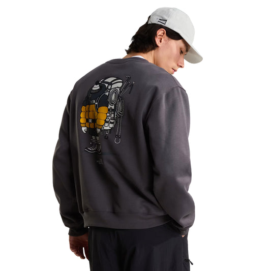 Sweatshirt unissexo The North Face Gear Up Get Out Relaxed Crew em Anthracite Grey — modelo masculino de costas, três quartos, meio corpo, polar cinzento antracite, gráfico Gear Up Get Out em serigrafia à base de água com equipamento de montanha colorido (mochila, corda, picaretas, cantil e botas), boné branco, calças cargo pretas, fundo branco.