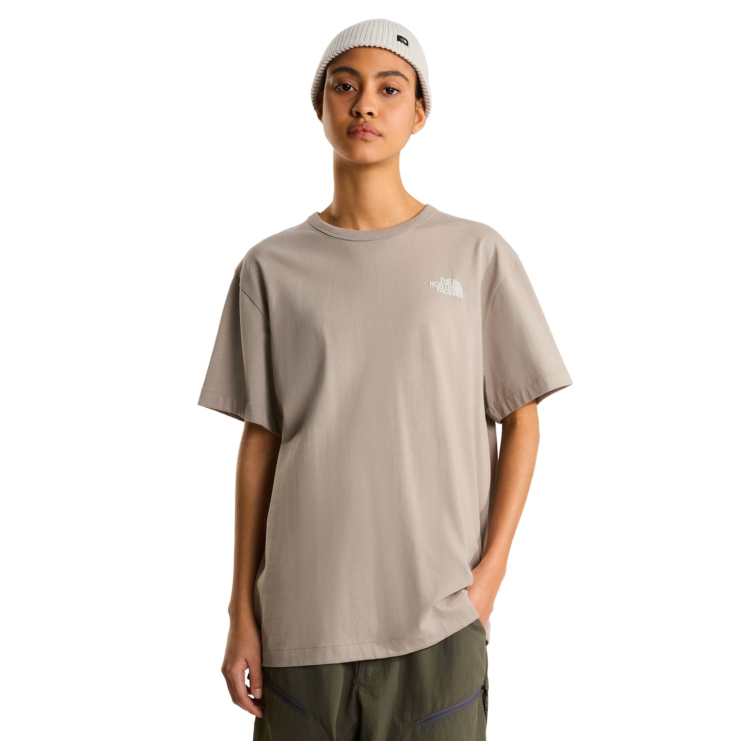 T-shirt The North Face NSE Slopes Relaxed em stone slab — modelo feminino de frente, meio corpo, corte relaxed oversized, logótipo The North Face bordado a branco no peito esquerdo, gola redonda canelada, gorro canelado branco com etiqueta TNF, fundo branco.