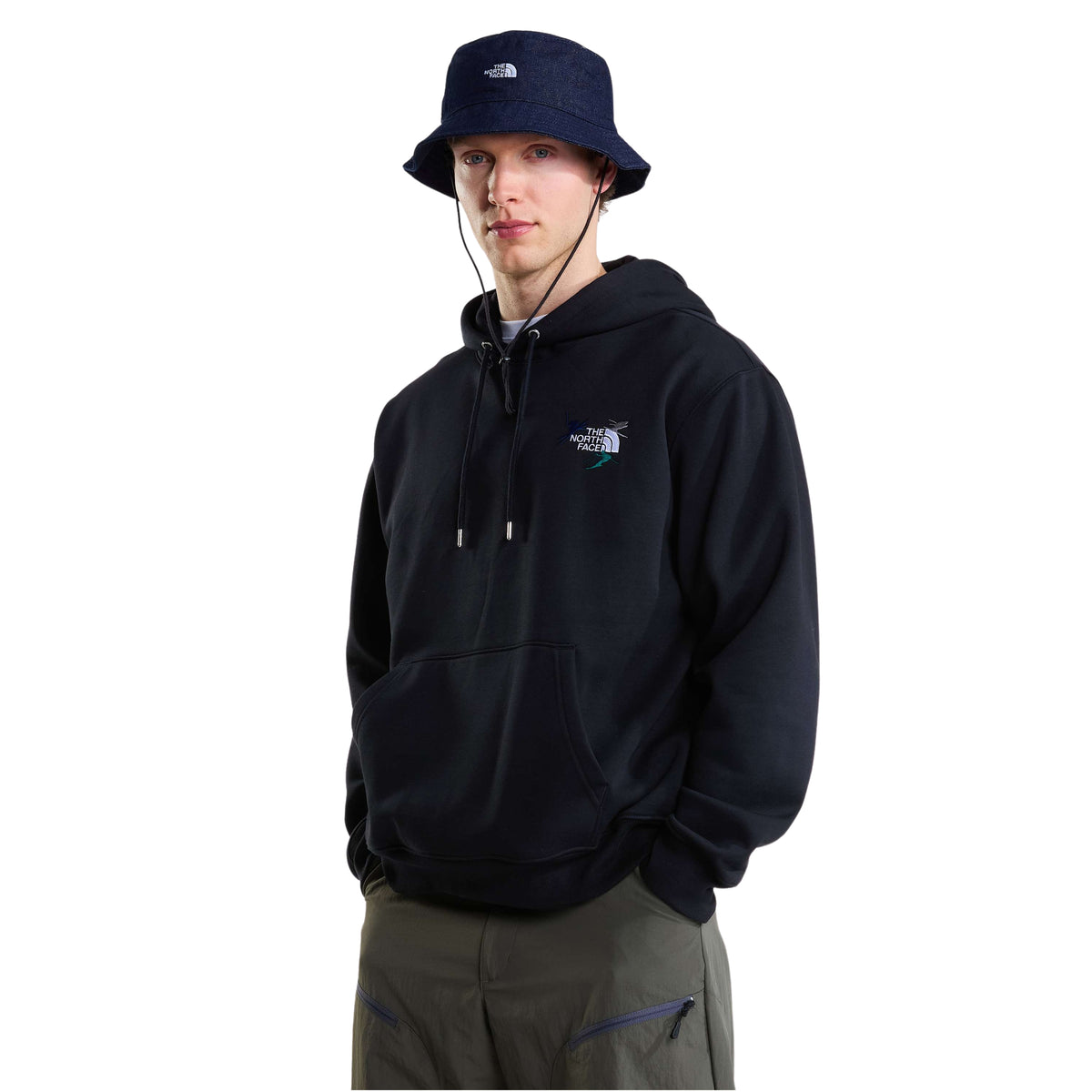 Modelo de frente com sweat com capuz The North Face Off Piste Embro preta, com bordado no peito e chapéu azul-escuro.