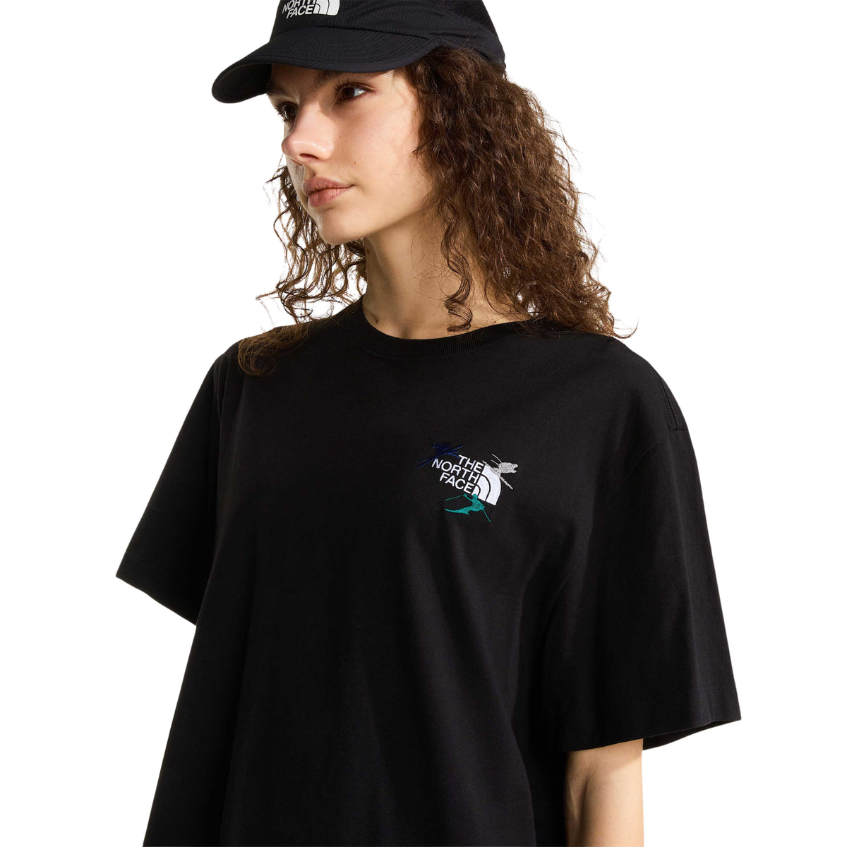Pormenor da frente da t-shirt The North Face Off Piste Embro preta numa modelo, com logótipo e esquiadores bordados no peito.