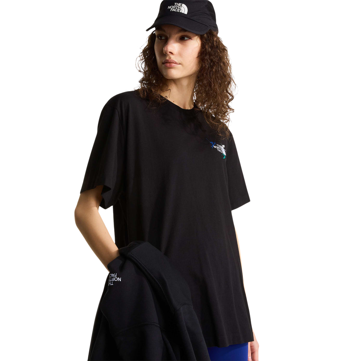 T-shirt The North Face Off Piste Embro preta numa modelo com casaco na mão, mostrando o comprimento e o corte descontraído.