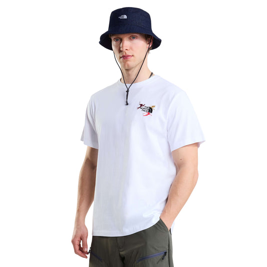 Modelo de frente com t-shirt The North Face Off Piste Embro branca de manga curta, com bordado no peito e chapéu azul-escuro.