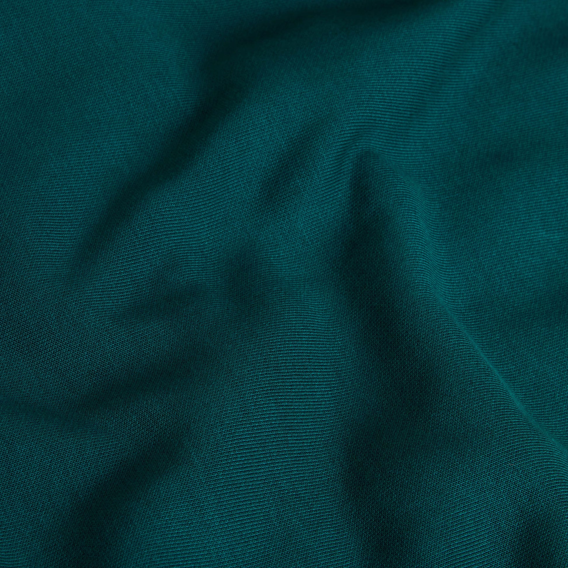 T-Shirt The North Face Retro Trail Relaxed em Pacific Teal — detalhe do tecido jersey em Pacific Teal, textura de malha com dobras suaves visíveis em close-up, fundo teal.