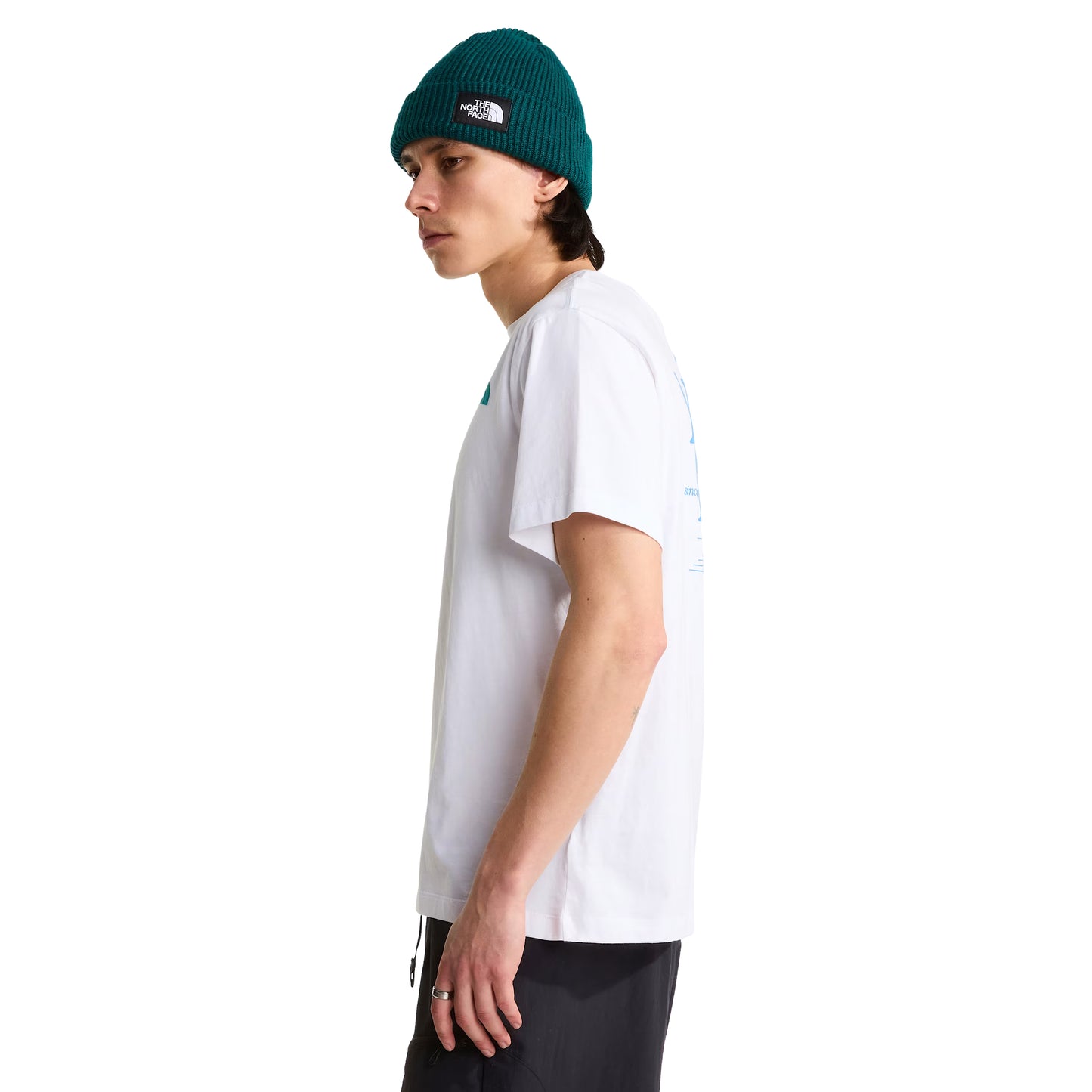 T-Shirt The North Face Retro Trail Relaxed em TNF White — modelo masculino de perfil direito, gorro TNF verde-teal com patch branco, calças pretas, logo TNF Retro Trail parcialmente visível no peito, corte relaxed com ombros descaídos, fundo branco.