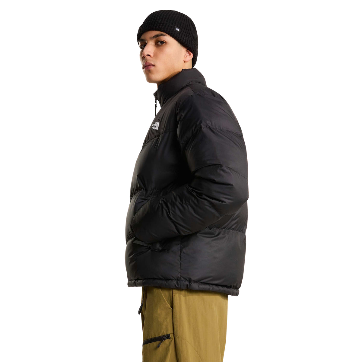 Casaco The North Face Saikuru preto em modelo de perfil, com a mão no bolso lateral, mostrando o volume da manga e a silhueta quadrada.
