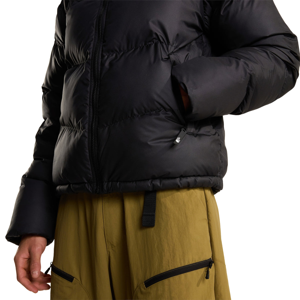 Pormenor da parte inferior do casaco The North Face Saikuru preto, com a mão no bolso lateral e destaque para a bainha e os painéis acolchoados.