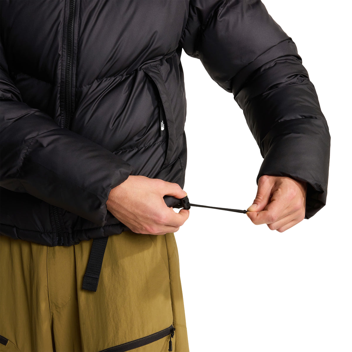 Pormenor do casaco The North Face Saikuru preto, com o modelo a puxar o cordão de ajuste da bainha.