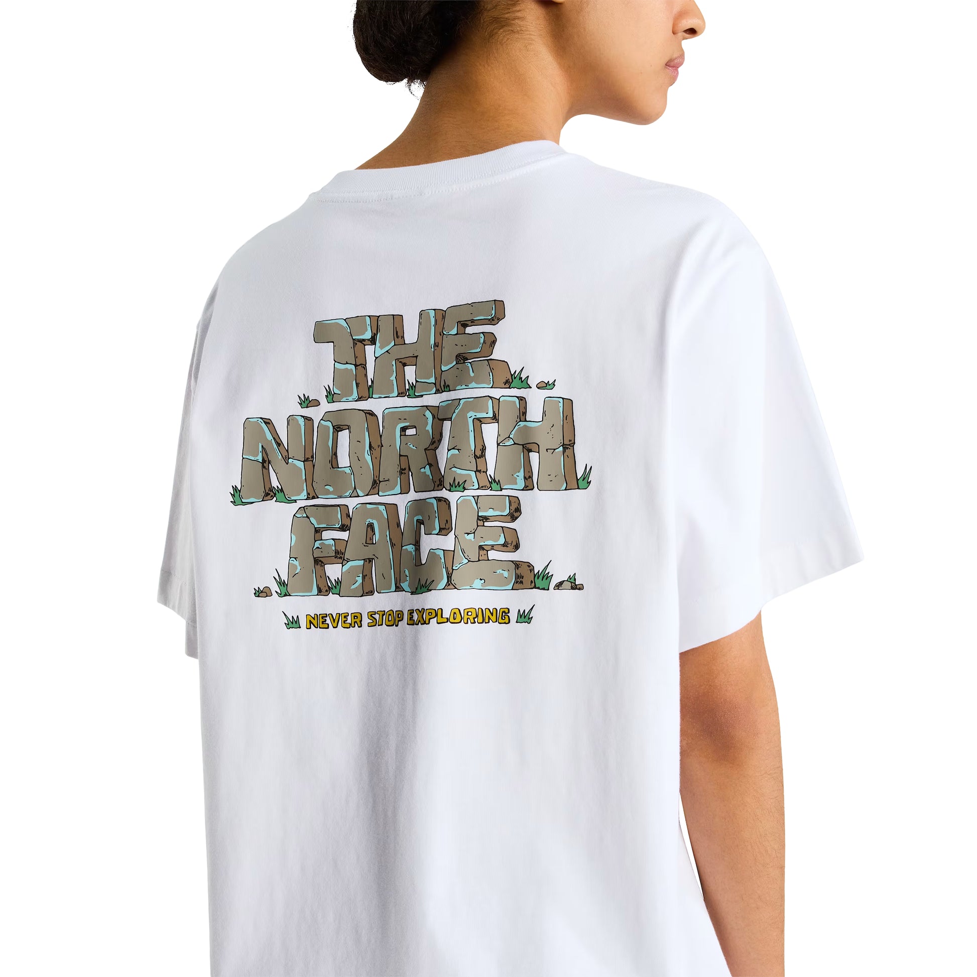 T-Shirt The North Face Stone Logo Relaxed em TNF White — detalhe das costas de modelo feminino, gráfico "The North Face" estilo pedra em cinza/verde musgo com detalhes de erva e inscrição "Never Stop Exploring" em amarelo na base visíveis em close-up, fundo branco.