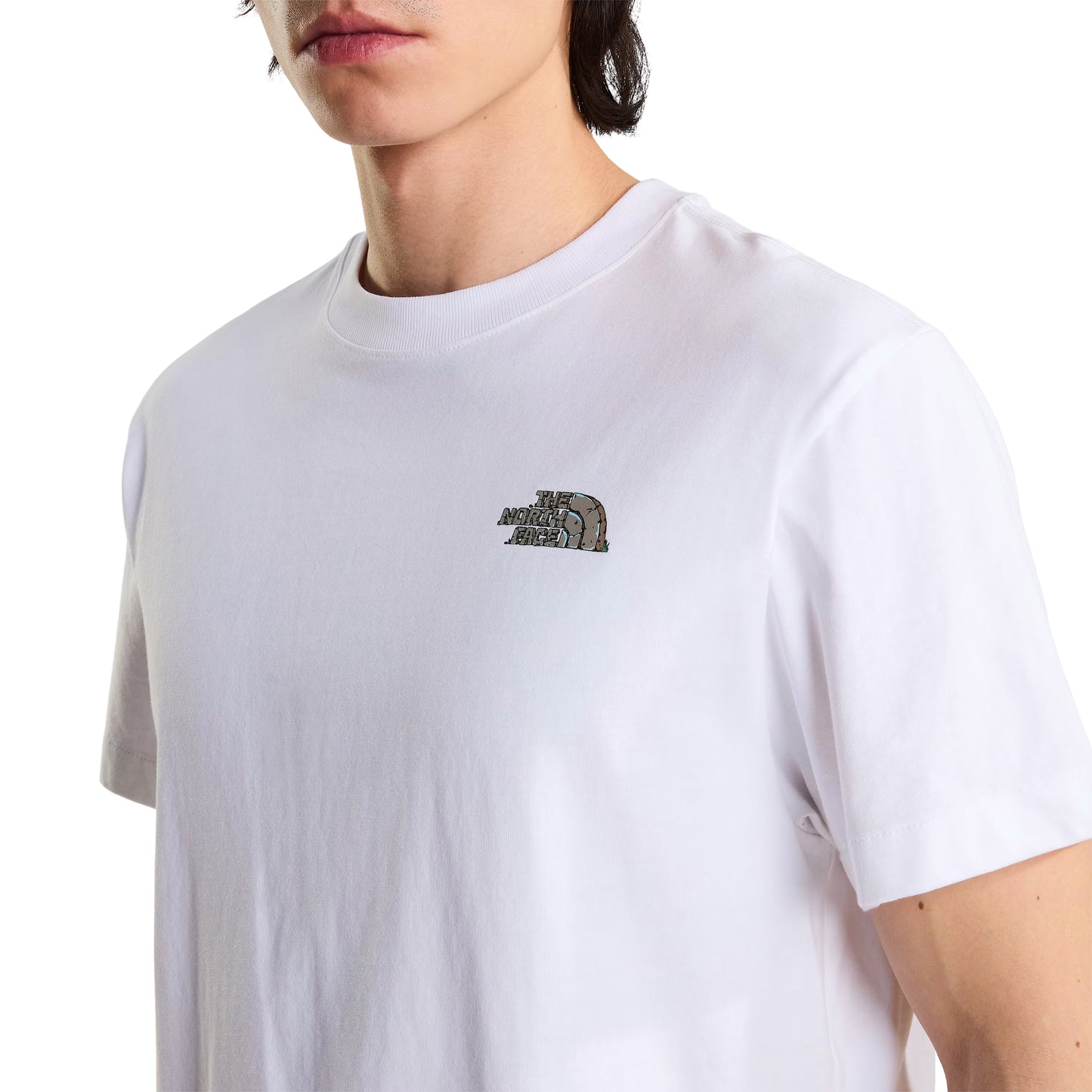 T-Shirt The North Face Stone Logo Relaxed em TNF White — detalhe do peito de modelo masculino, logo TNF Stone Logo em pedra cinza/verde musgo com half-dome no peito esquerdo e gola redonda em TNF White visíveis em close-up, fundo branco.