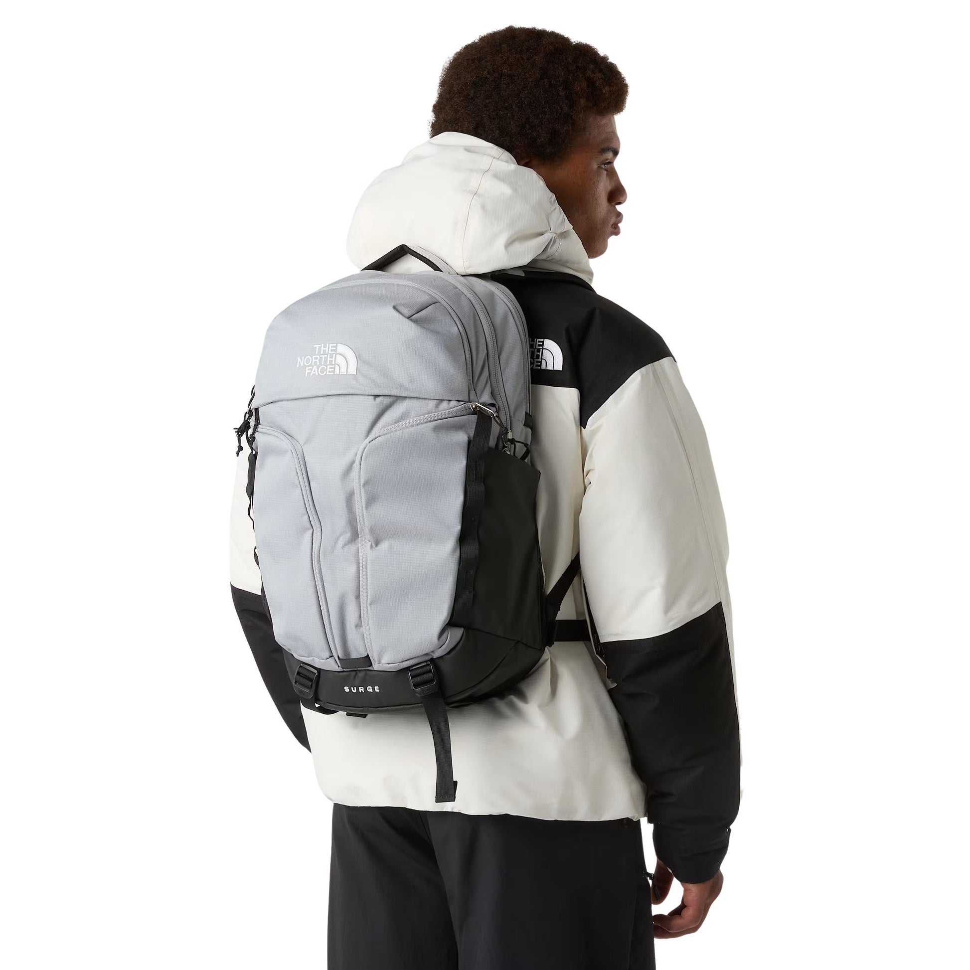 Mochila unissexo The North Face Surge em Cinza Escuro Heather Meld/Preto TNF. Foto da mochila nas costas.