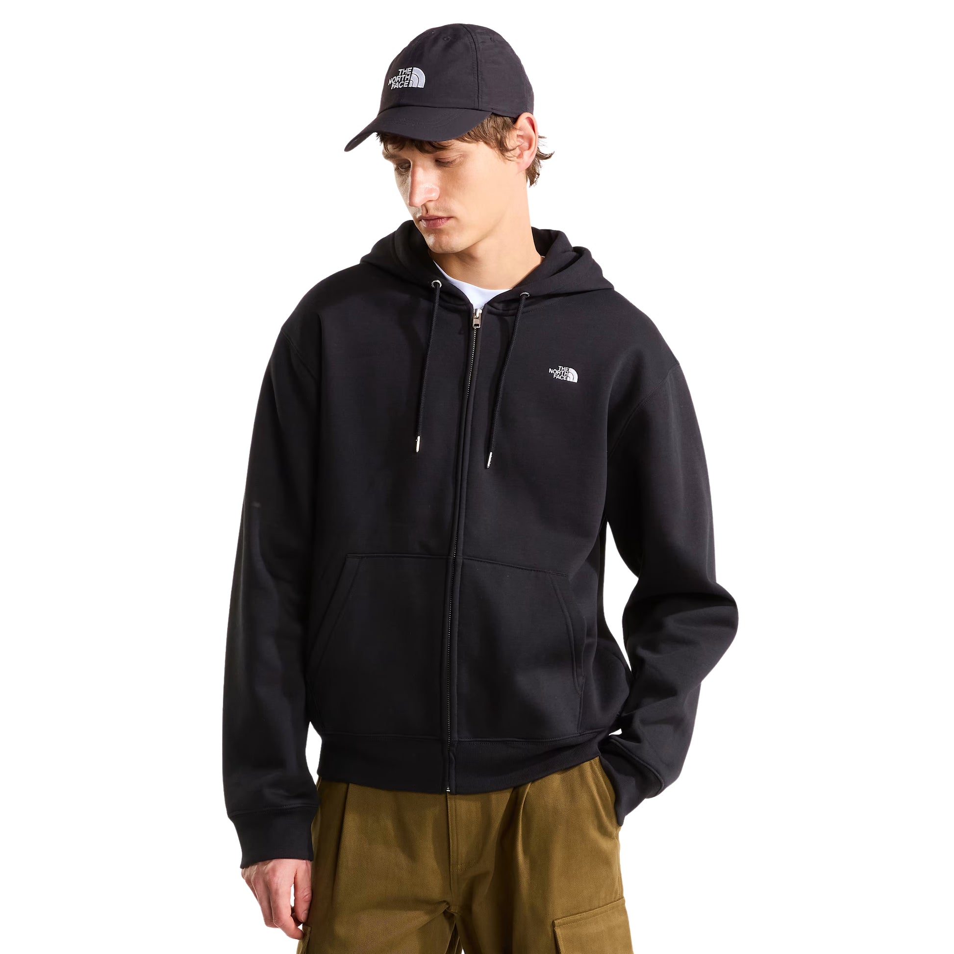 Hoodie The North Face TNF Essential Simple Dome Relaxed Full Zip em TNF Black — modelo masculino de frente a 3/4, boné TNF preto, calças cargo verde-oliva, hoodie fechada com logótipo TNF half-dome bordado em branco no peito esquerdo, capuz com cordão branco e bolso canguru visíveis, fundo branco.