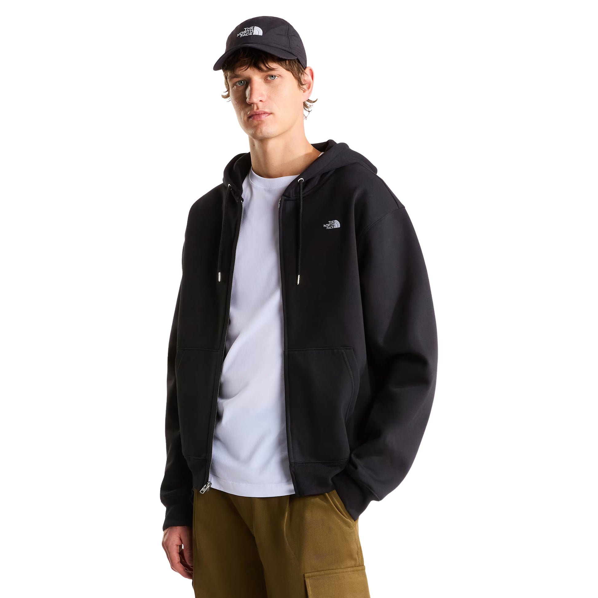 Hoodie The North Face TNF Essential Simple Dome Relaxed Full Zip em TNF Black — modelo masculino de frente a 3/4, boné TNF preto, hoodie aberta sobre t-shirt branca TNF, logótipo TNF half-dome bordado em branco no peito esquerdo, fecho de correr integral prateado e bolso canguru dividido visíveis, fundo branco.