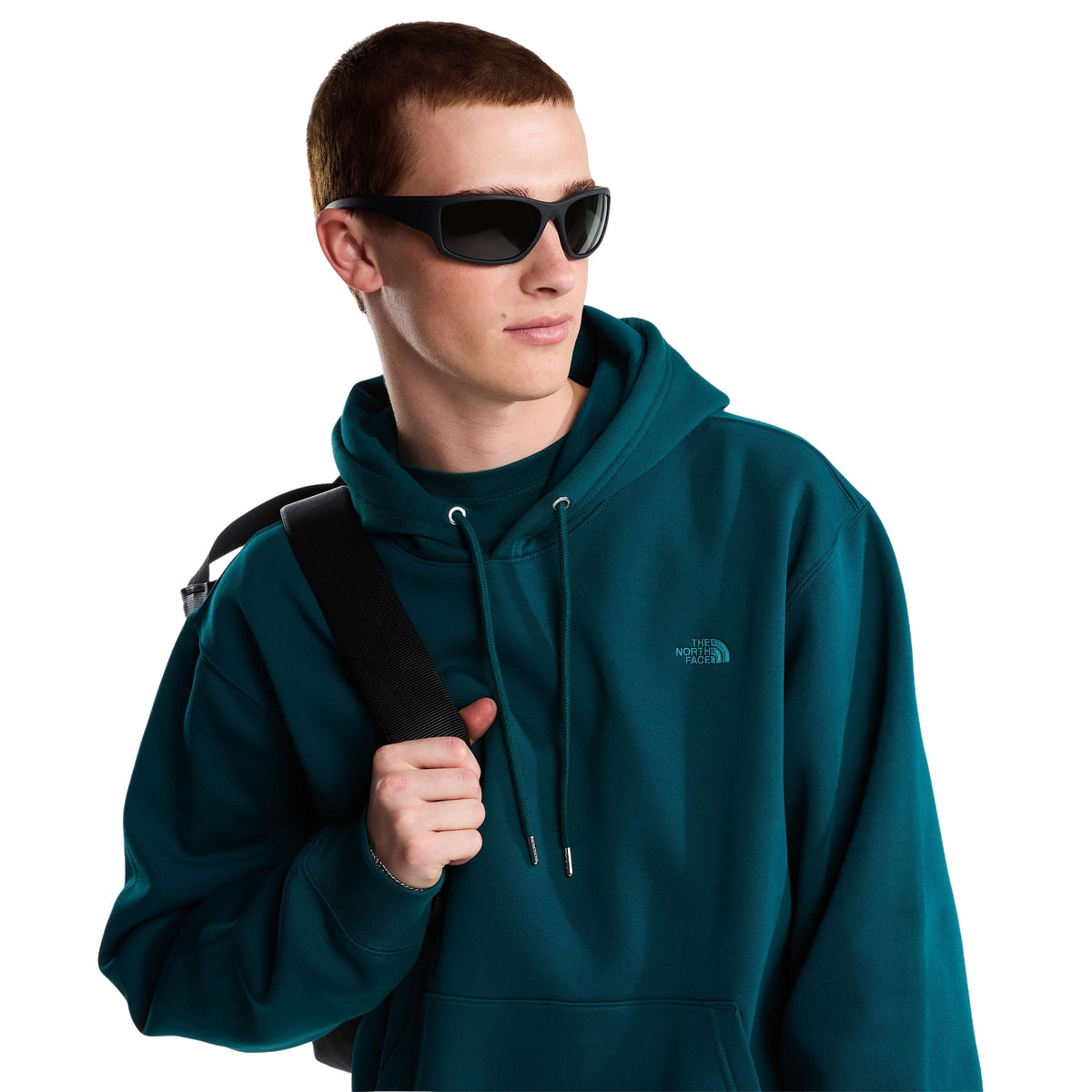 Modelo com sweat The North Face Essential Simple Dome Pacific Teal, óculos de sol e mochila ao ombro, mostrando o capuz com cordões.