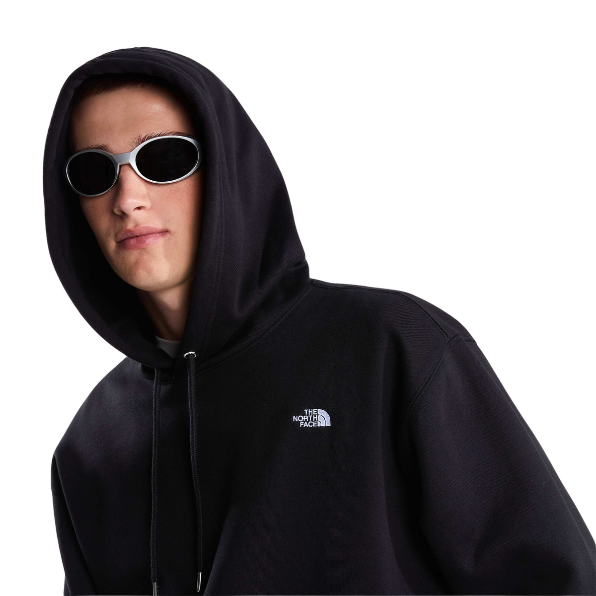 Vista aproximada da sweat The North Face Essential Simple Dome preta num modelo com o capuz colocado, óculos de sol e logótipo branco no peito.