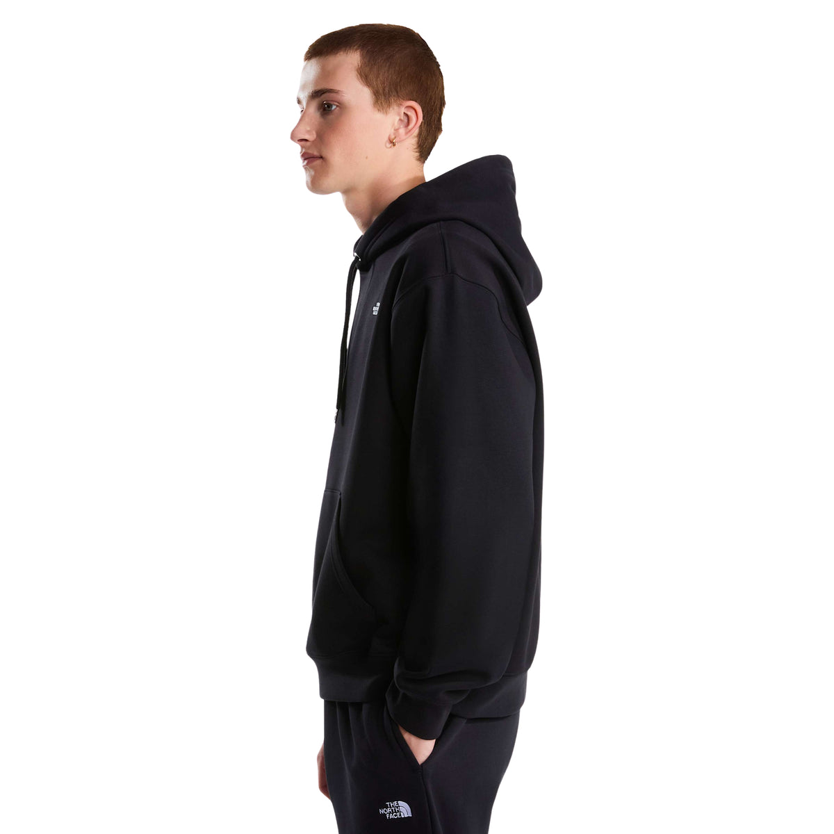 Vista lateral da sweat com capuz The North Face Essential Simple Dome preta num modelo, mostrando o corte descontraído e o punho canelado.