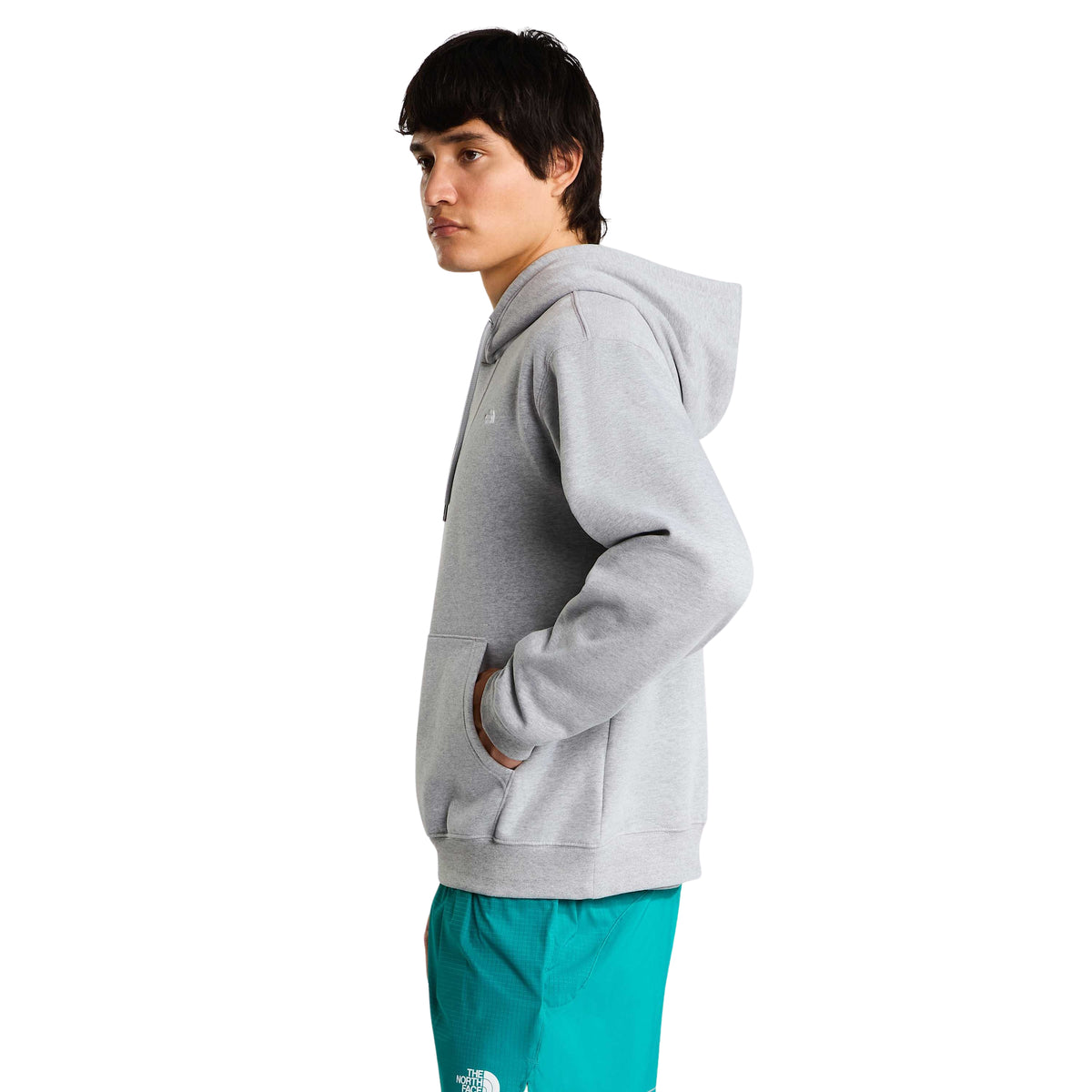 Vista lateral da sweat The North Face Essential Simple Dome cinza-claro mesclado num modelo com a mão no bolso canguru.