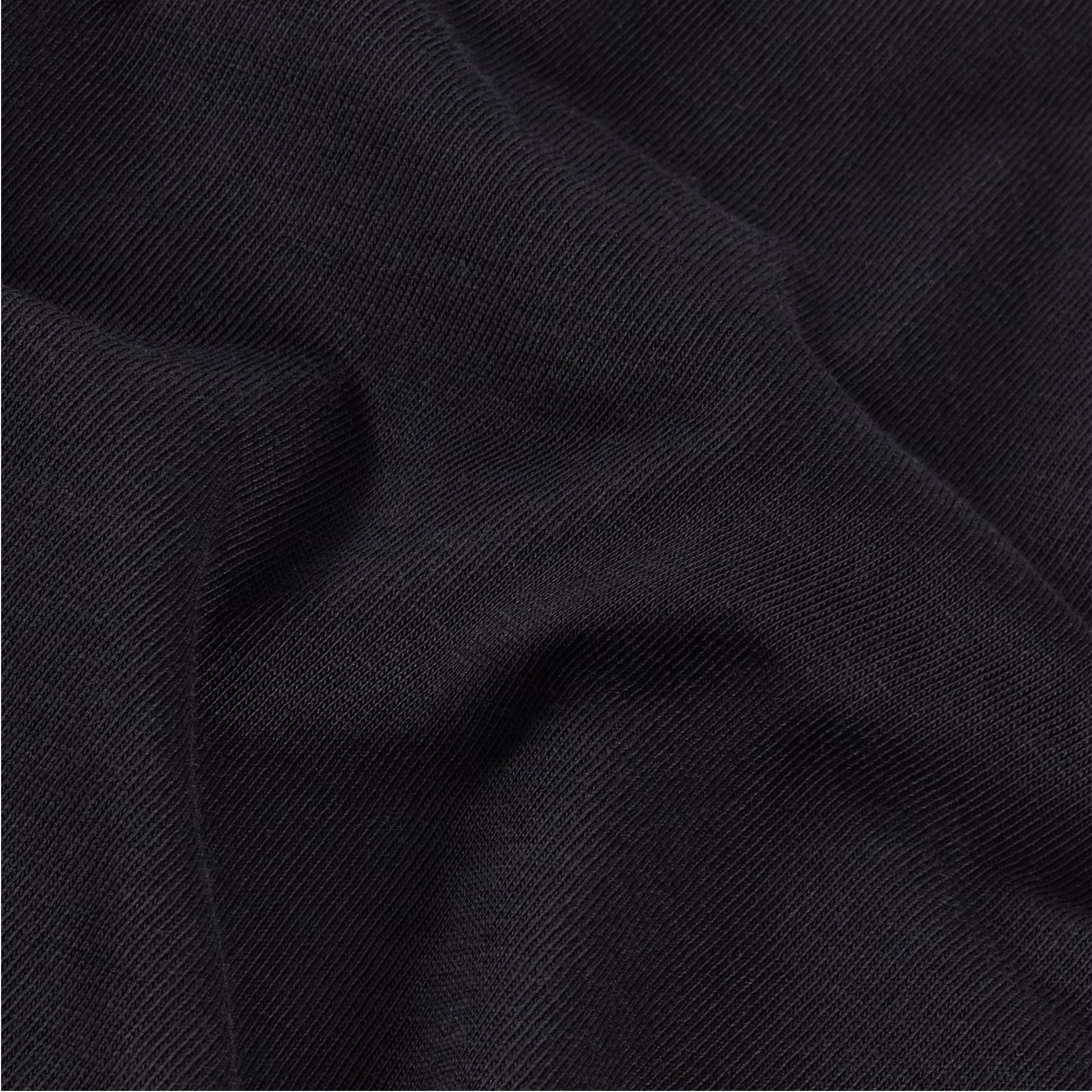 T-Shirt The North Face Vertical Regular em TNF Black — detalhe do tecido jersey em TNF Black, textura de malha 165 g/m² com dobras suaves visíveis em close-up, fundo preto.