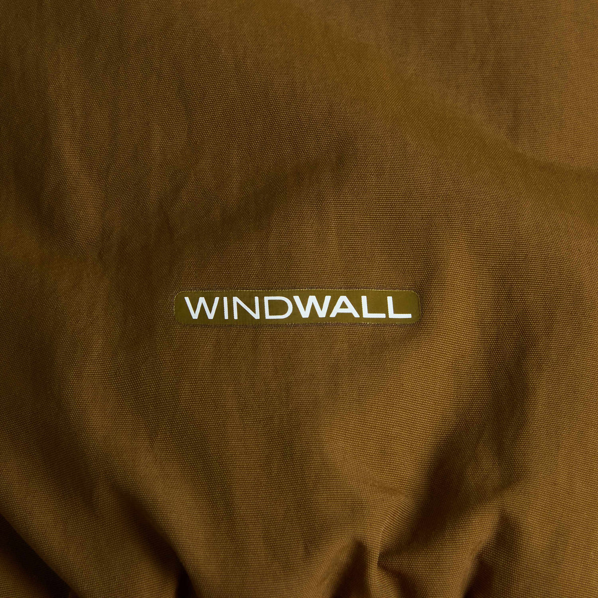 Pormenor do logótipo WindWall™ branco sobre o tecido Caraway Seed do casaco reversível The North Face Yumiori.