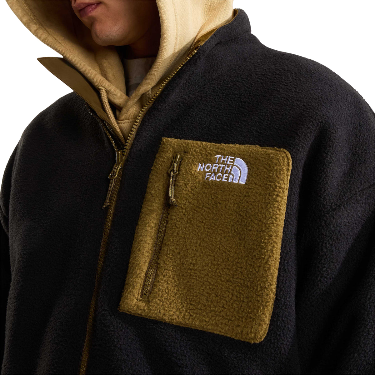 Pormenor do bolso de peito Caraway Seed com fecho e logótipo branco bordado no casaco polar The North Face Yumiori.