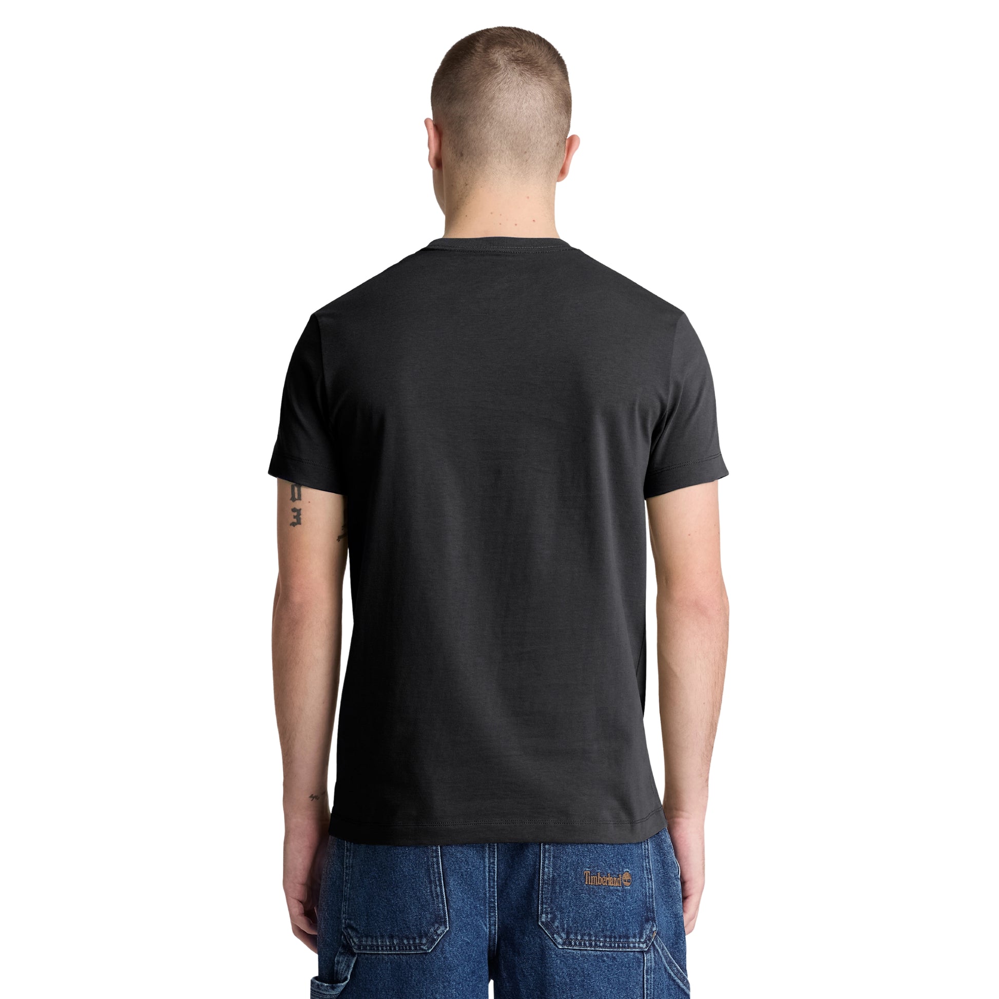 T-shirt Timberland Dunstan River em Black — vista traseira com modelo, corpo inteiro, costas limpas, corte slim visível, combinado com calções denim azul Timberland e botas wheat.