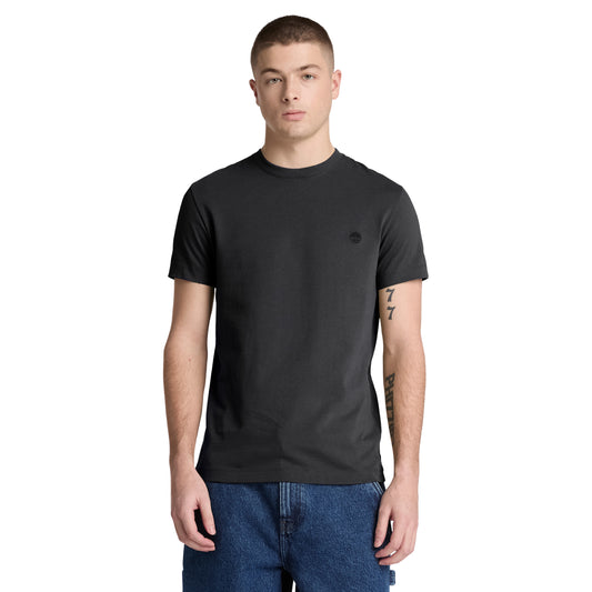 T-shirt Timberland Dunstan River em Black — vista frontal com modelo, meio corpo, logótipo árvore Timberland bordado em preto tonal no peito esquerdo, gola redonda canelada, corte slim, combinado com calções denim azul.