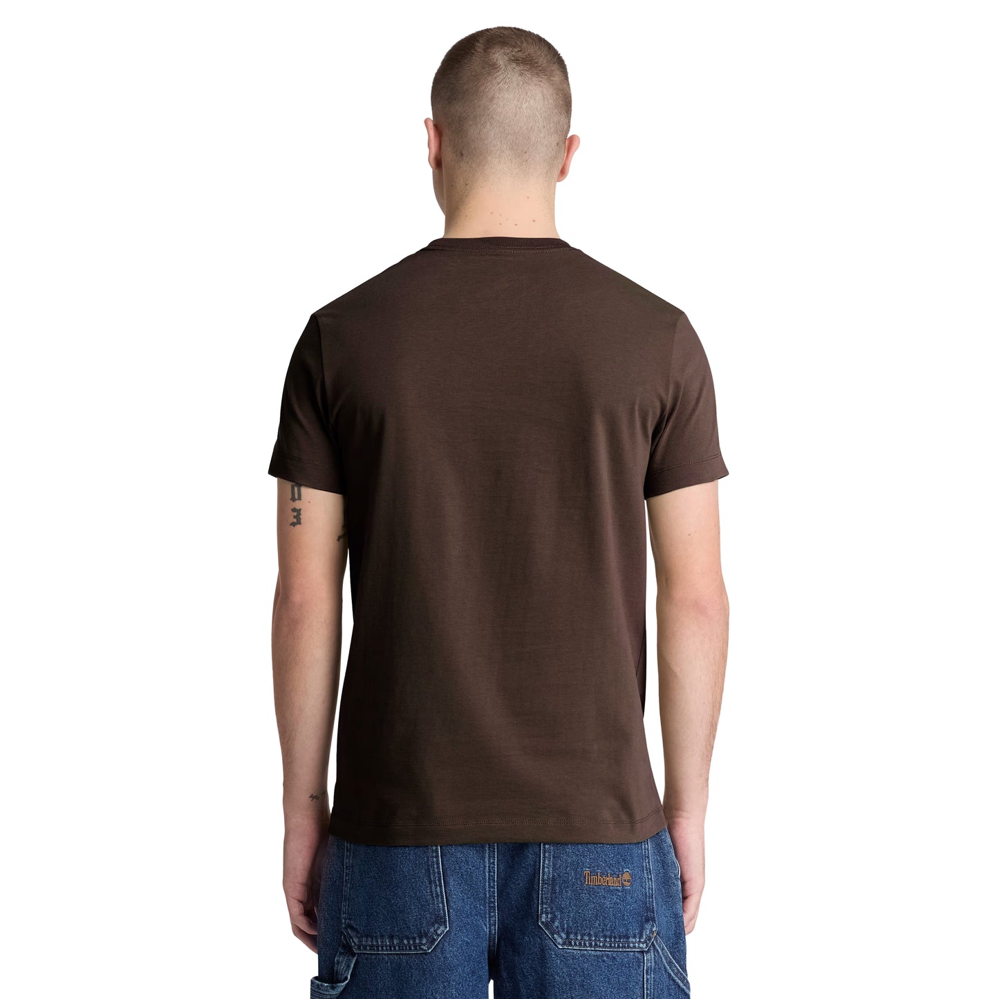 T-shirt Timberland Dunstan River em Mole — vista traseira com modelo, meio corpo, costas limpas, gola redonda canelada e corte slim visíveis, combinado com calções denim azul.