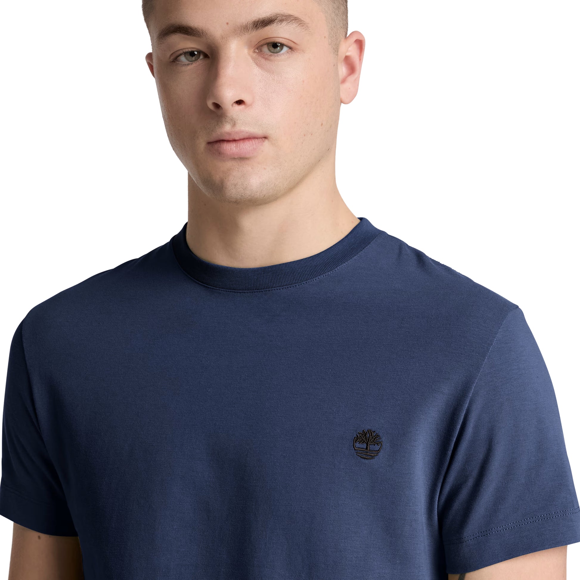 T-shirt Timberland Dunstan River em Naval Academy — detalhe do logótipo árvore Timberland bordado em preto tonal no peito esquerdo e gola redonda canelada, close-up com modelo.