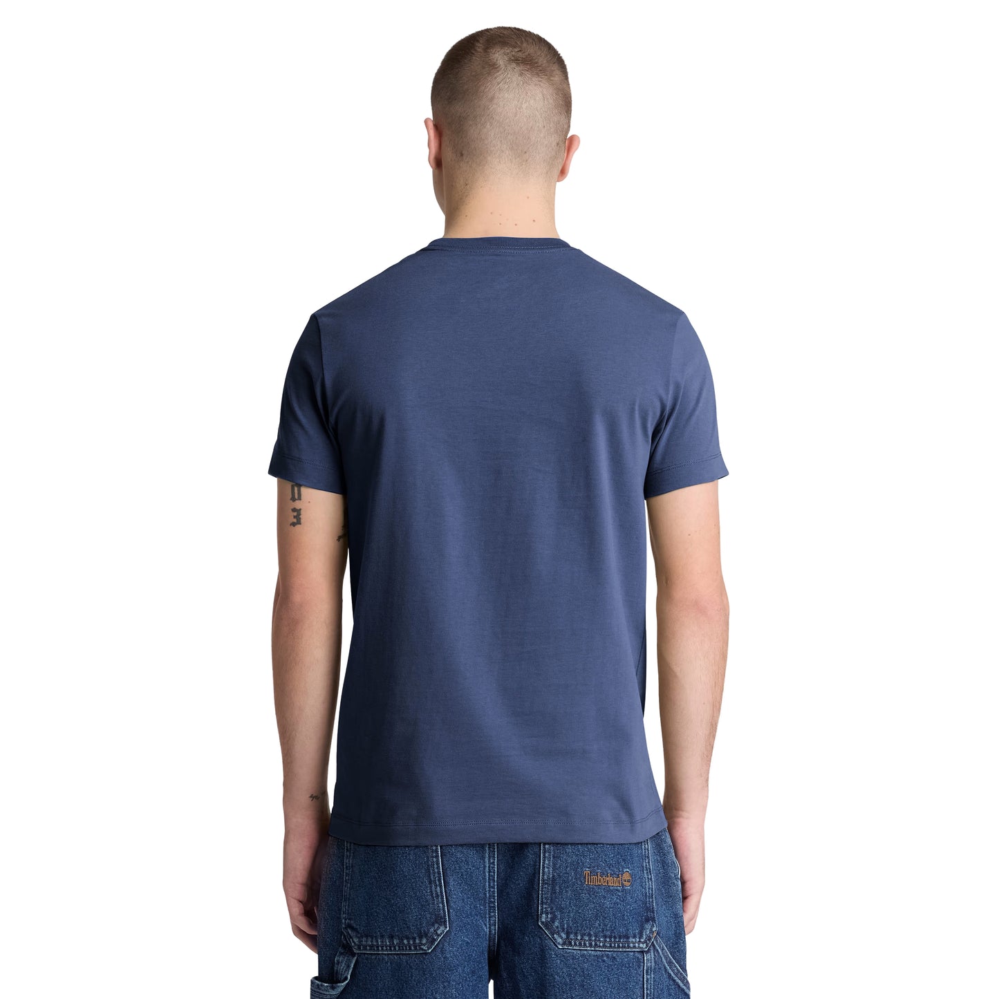 T-shirt Timberland Dunstan River em Naval Academy — vista traseira com modelo, meio corpo, costas limpas, gola redonda canelada e corte slim visíveis, combinado com calções denim azul Timberland.
