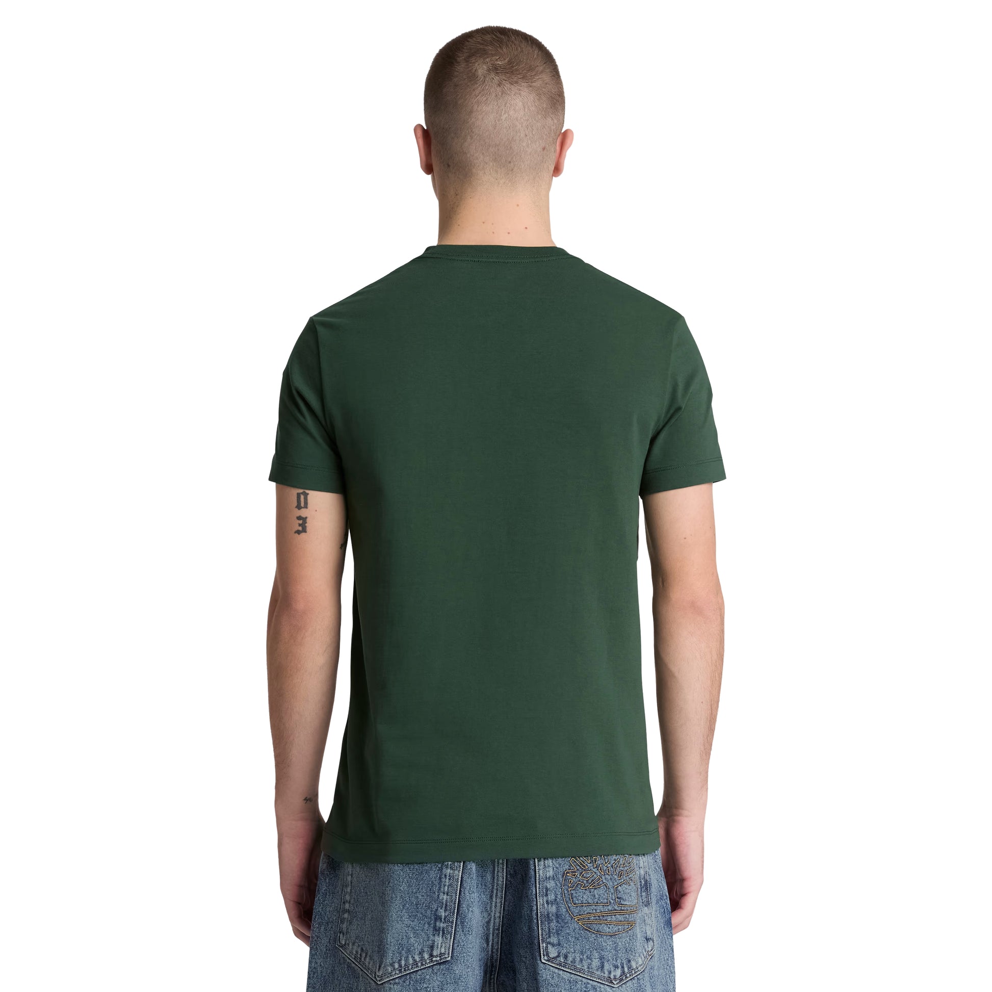 T-shirt Timberland Dunstan River em Sycamore — vista traseira com modelo, meio corpo, costas limpas, gola redonda canelada e corte slim visíveis, combinado com calças de ganga azul Timberland.