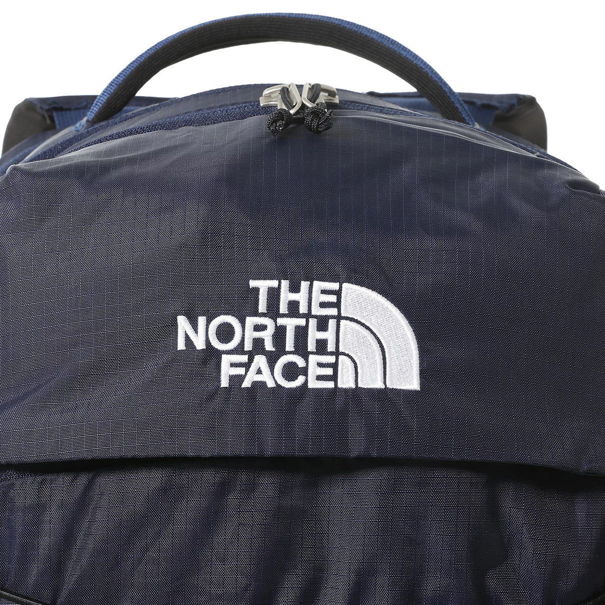 The North Face Borealis Backpack TNF Navy/TNF Black. Foto de detalhe do logotipo bordado, fecho e pega superior.